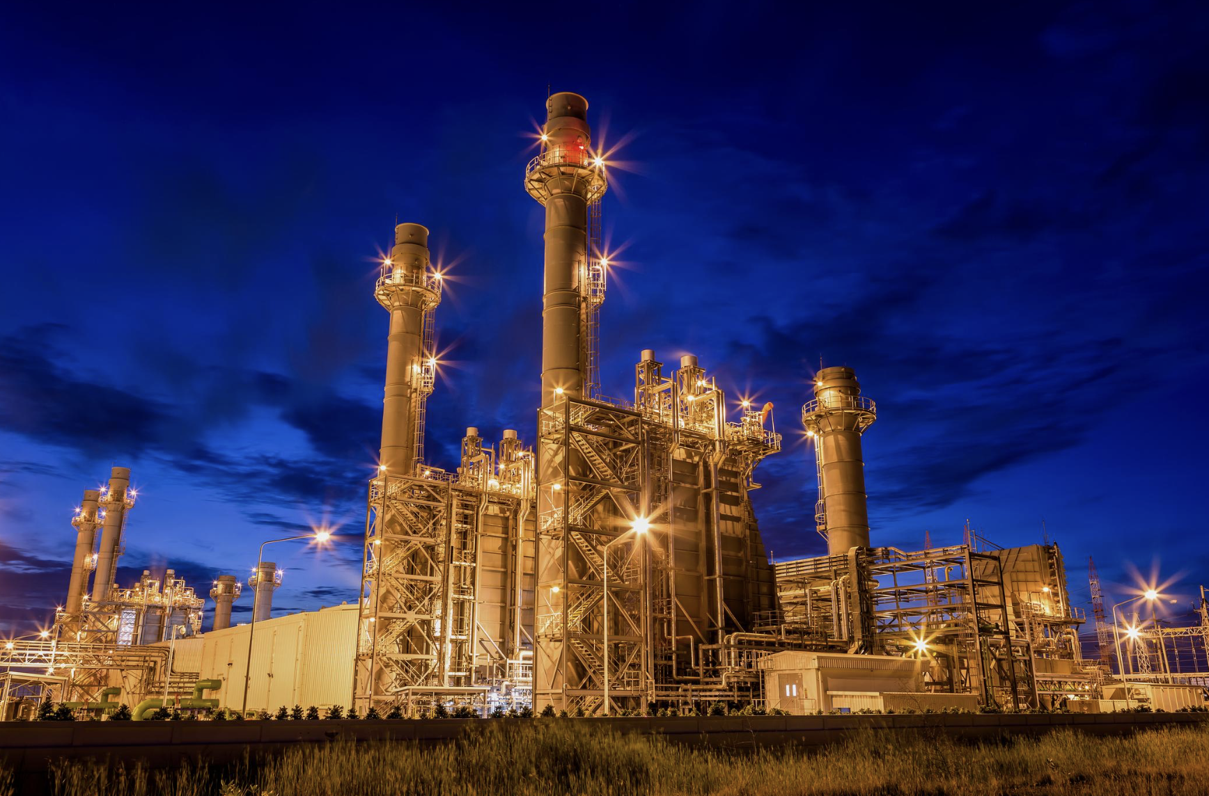 Combined-cycle power plant illuminated against a deep blue sky